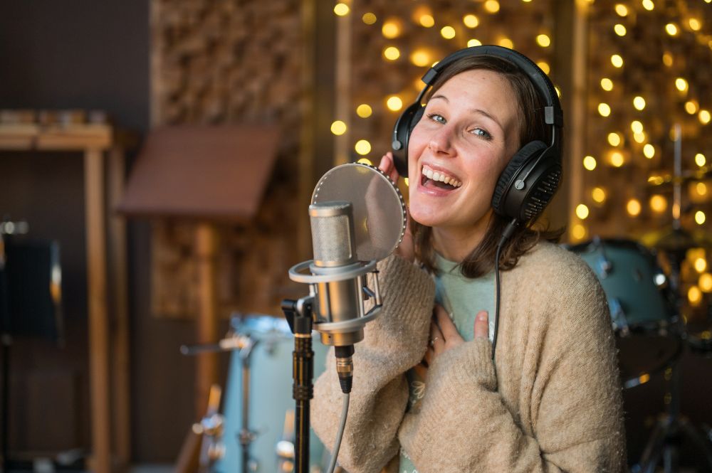 Frau singt voller Freude in einem Tonstudio vor einem Mikro.